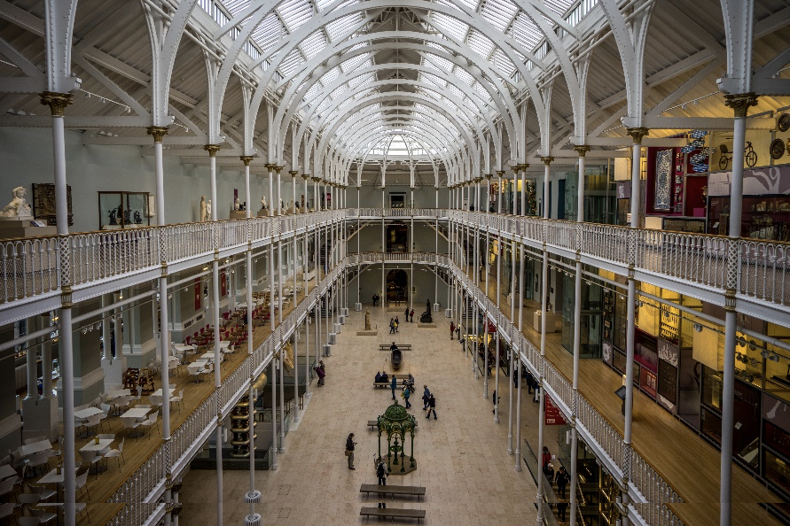 a group of people at a train station with National Museum of Scotland in the background